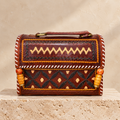 Brown Kutch Embroidery Hut Handbag on travertine pedestal