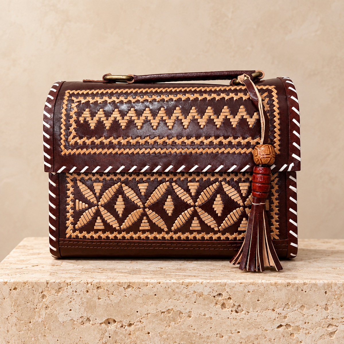Brown & Tan Embroidery Hut Handbag on travertine pedestal