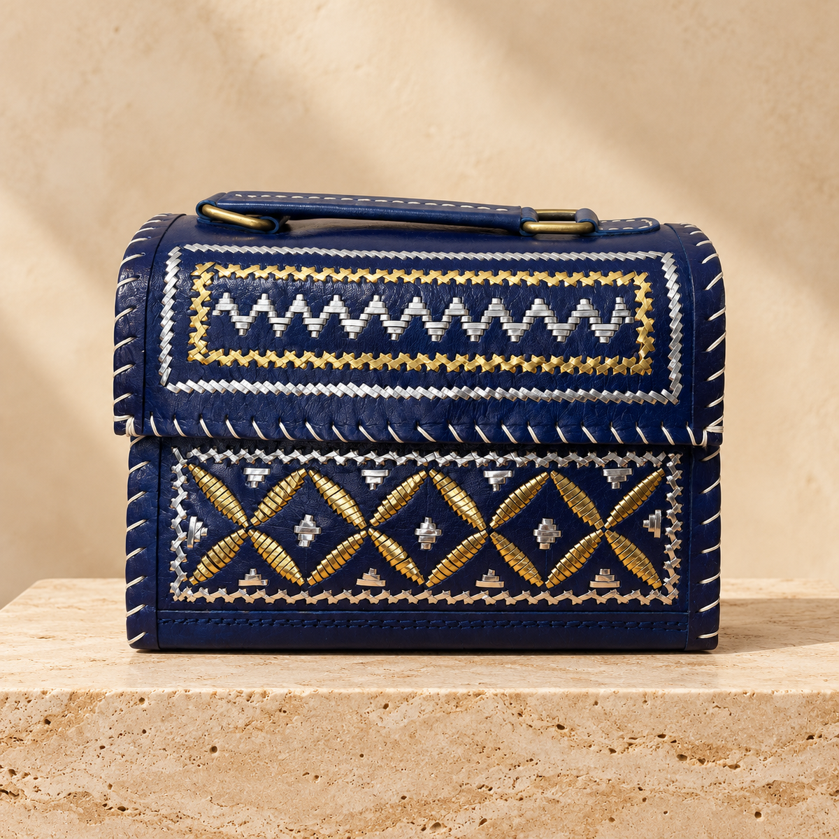 Navy metallic embroidery Hut Handbag on travertine pedestal